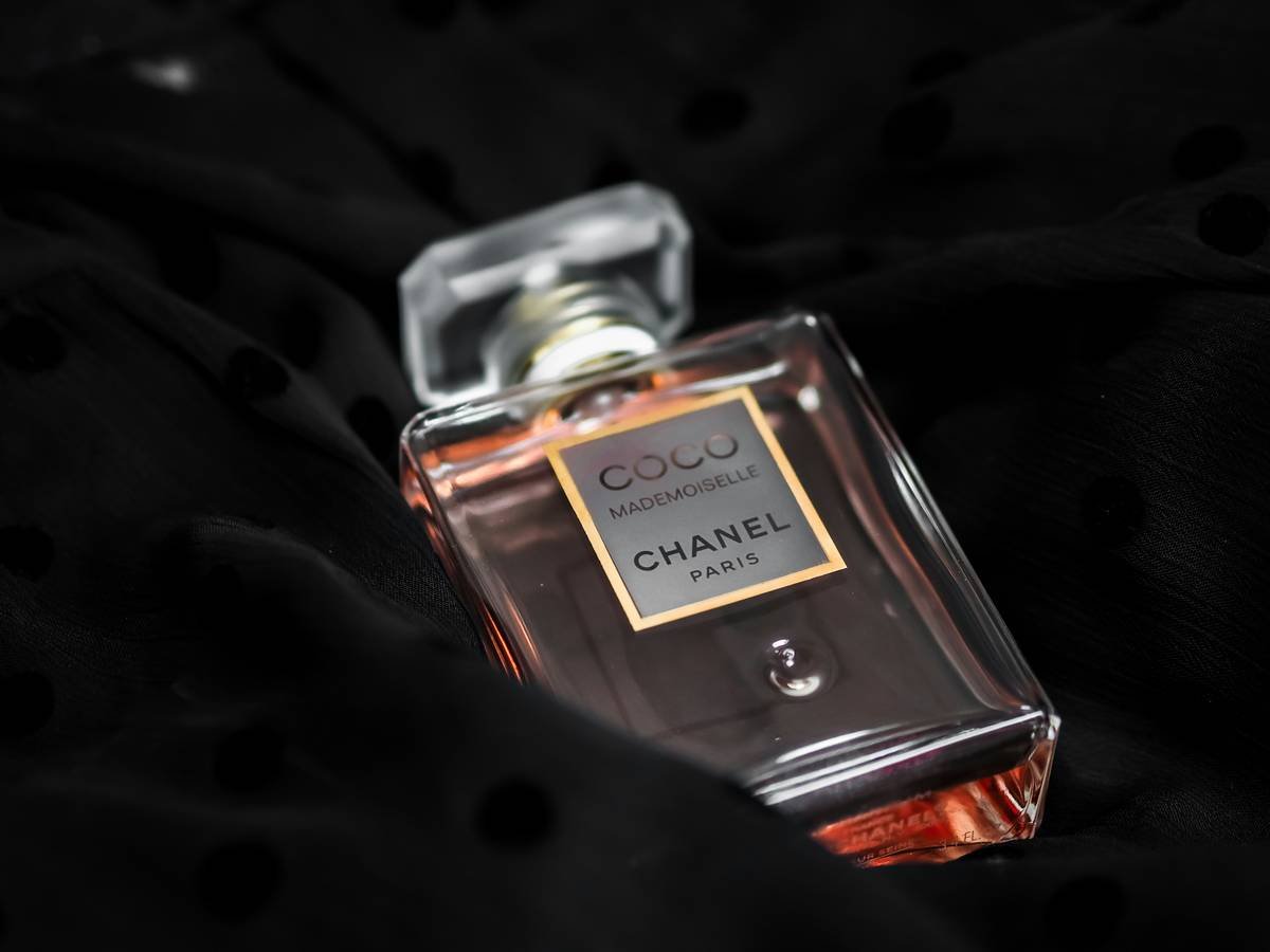 A man testing good male cologne that lasts long on his wrist with fragrance bottles in the background